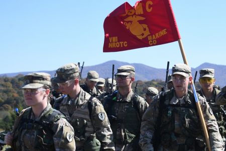 Marine ROTC cadets within the Naval ROTC Program train in the field and carry a US Marine Corps flag.